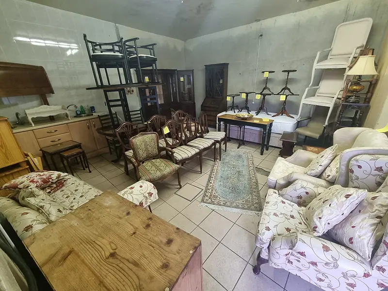 Large room filled with stacked chairs, sofas, tables and cabinets