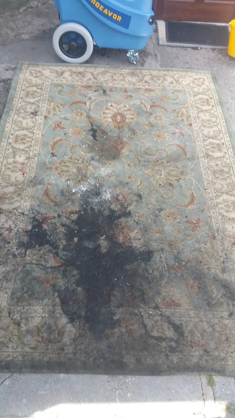 Traditional rug with a large dark stain before cleaning