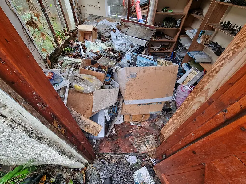 Garden outbuilding full of boxes and junk, seen through its open timber doors