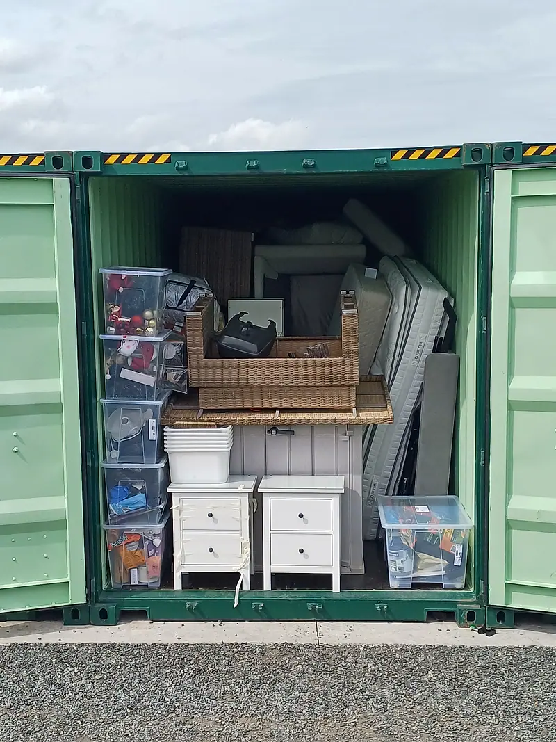 Open storage container packed with furniture and boxes before clearance