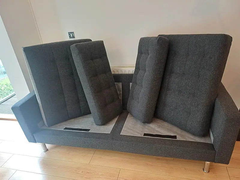 Grey fabric sofa with its cushions lifted off the base during cleaning