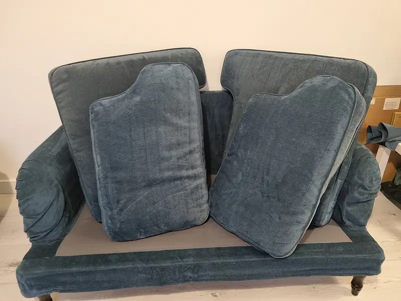 Small blue upholstered two-seater sofa waiting for removal