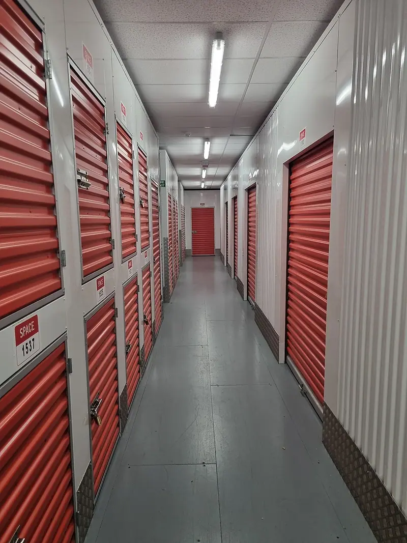 Self-storage corridor lined with red roller-shutter units