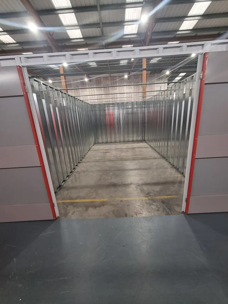 Long, empty self-storage unit with metal walls and a concrete floor after clearance