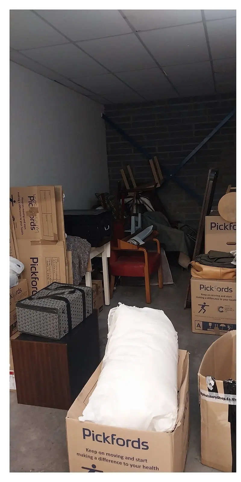 Storage unit packed with furniture, removal boxes and bags before clearance
