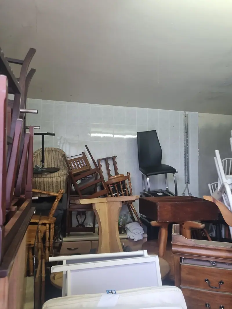 Storage unit packed with chairs, tables and wooden furniture before clearance