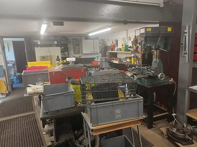 Large workshop crowded with benches, crates and machinery before clearance